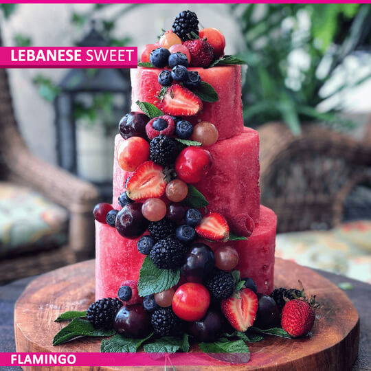 A vibrant fruit cake made from watermelon, beautifully decorated with an assortment of fresh fruits.