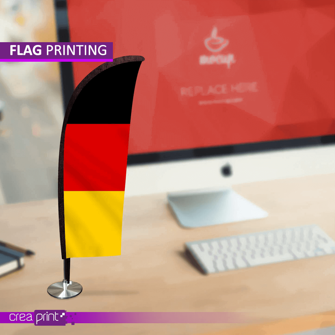 Custom desk flag with a sleek base, displayed on an office desk next to a laptop.