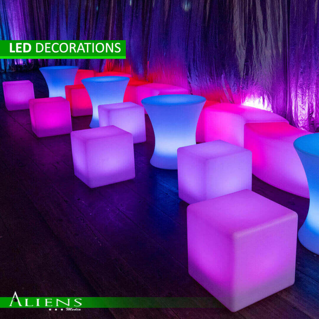 A group of people laughing and enjoying drinks while sitting on a glowing LED sofa.